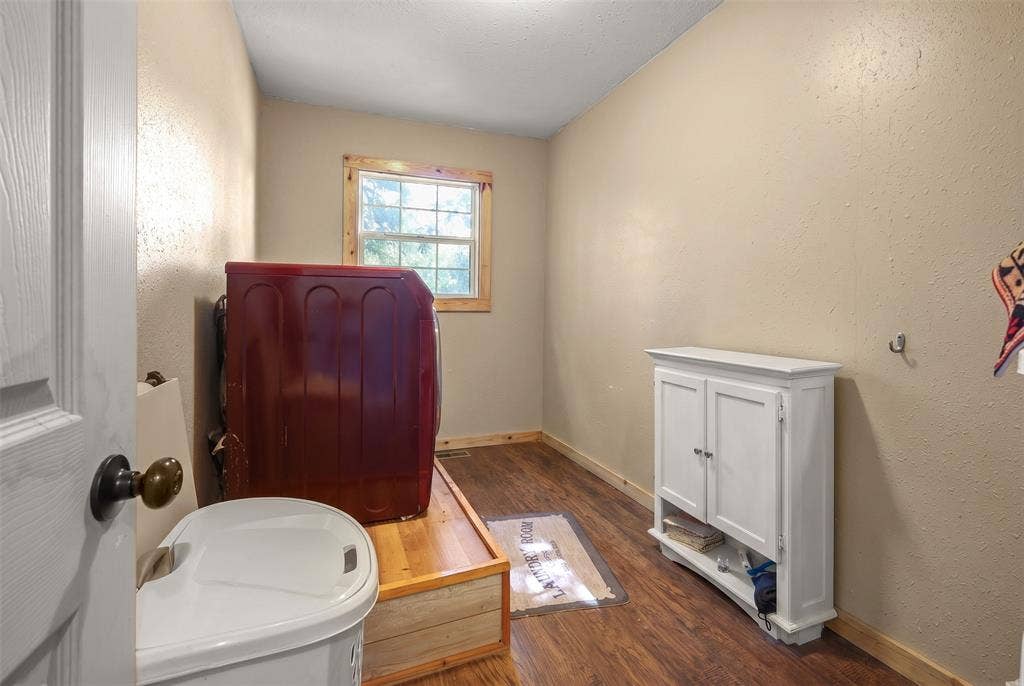 28300 County Road 2100, Kemp, TX 75143 Utility room featuring wood-finish flooring, a window with wood trim, and neutral-toned walls