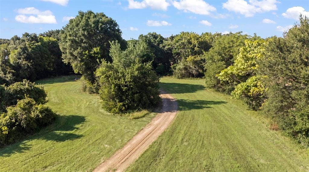 28300 County Road 2100, Kemp, TX 75143 Expansive cleared land featuring a dirt track, surrounded by mature trees and natural foliage