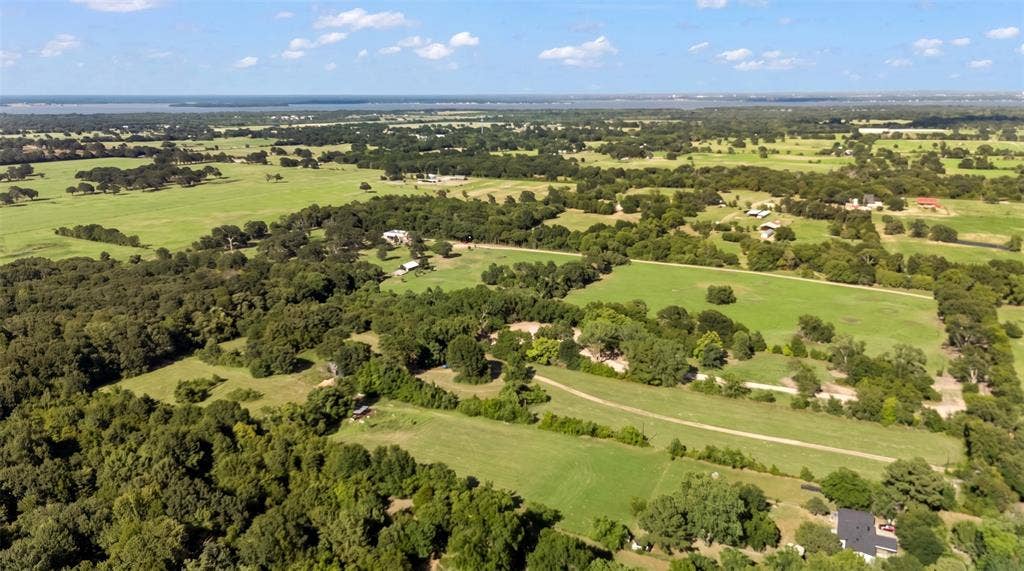 28300 County Road 2100, Kemp, TX 75143 Expansive rural landscape featuring extensive green pastures, mature tree coverage, and a distant body of water