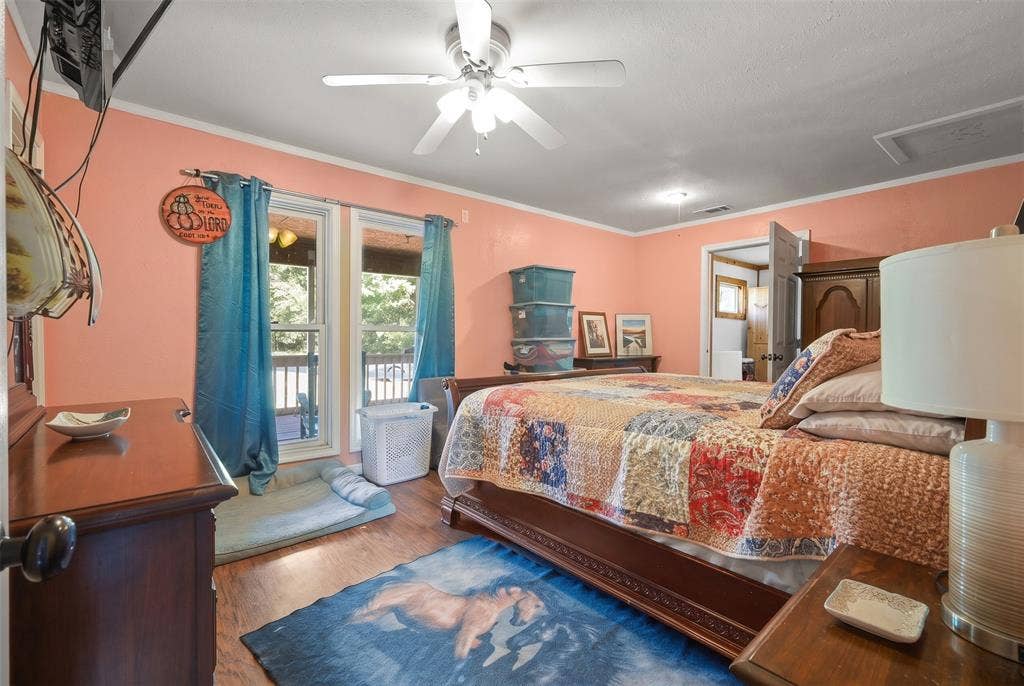 28300 County Road 2100, Kemp, TX 75143 Spacious room with wood-finish flooring, featuring a ceiling fan, crown molding, and direct outdoor access through twin windows