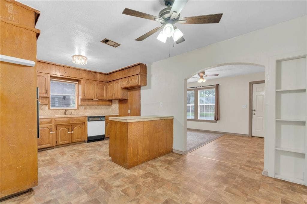 1113 Hudgins Avenue, Fort Worth, TX 76111 Kitchen featuring wood cabinetry, a built-in dishwasher, tile backsplash, and an island with a contrasting countertop