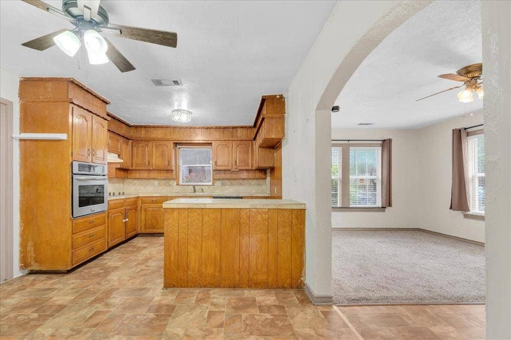 1113 Hudgins Avenue, Fort Worth, TX 76111 Kitchen featuring wood cabinetry, built-in oven, tile backsplash, and an island with countertop space