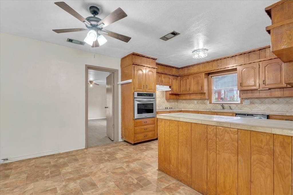 1113 Hudgins Avenue, Fort Worth, TX 76111 Kitchen featuring wood-panel cabinetry, light-toned countertops, and a built-in double oven