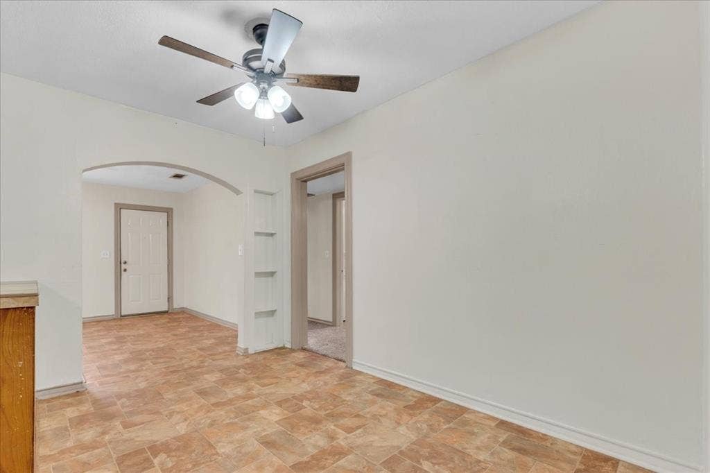 1113 Hudgins Avenue, Fort Worth, TX 76111 Neutral wall paint, patterned floor tiling, an arched doorway, and a ceiling fan with light fixture