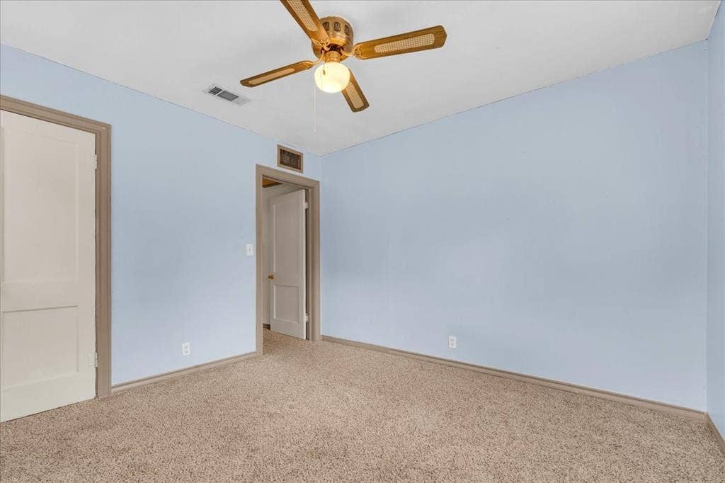 1113 Hudgins Avenue, Fort Worth, TX 76111 Carpeted room featuring light blue walls, a ceiling fan with light fixture, and two panel doors with contrasting trim