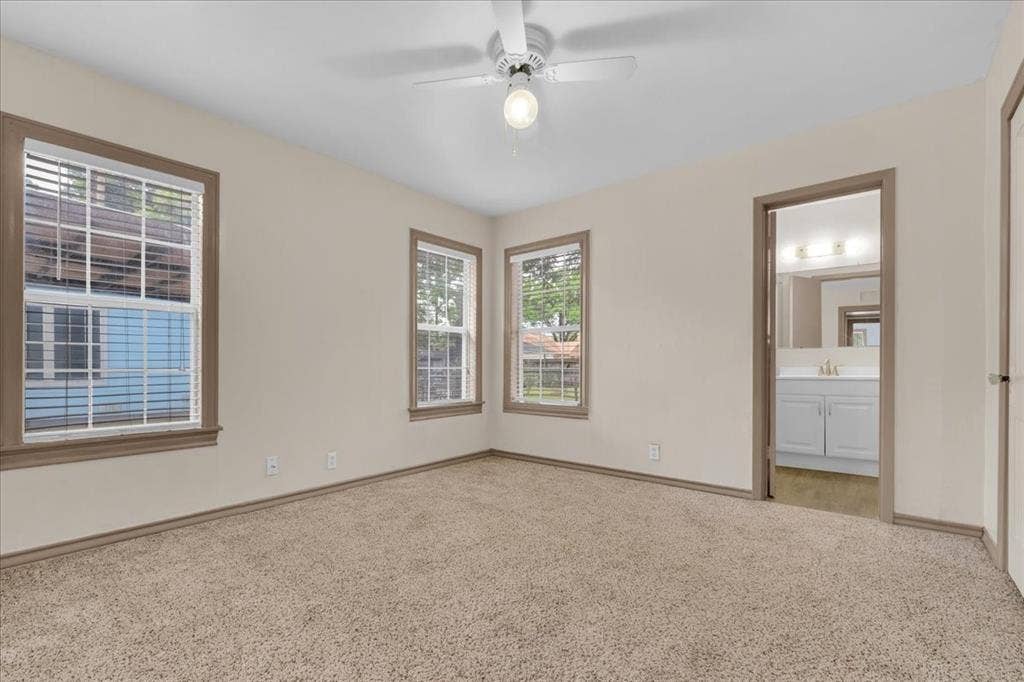 1113 Hudgins Avenue, Fort Worth, TX 76111 Carpeted room featuring multiple windows with blinds, a ceiling fan with light fixture, and neutral wall paint