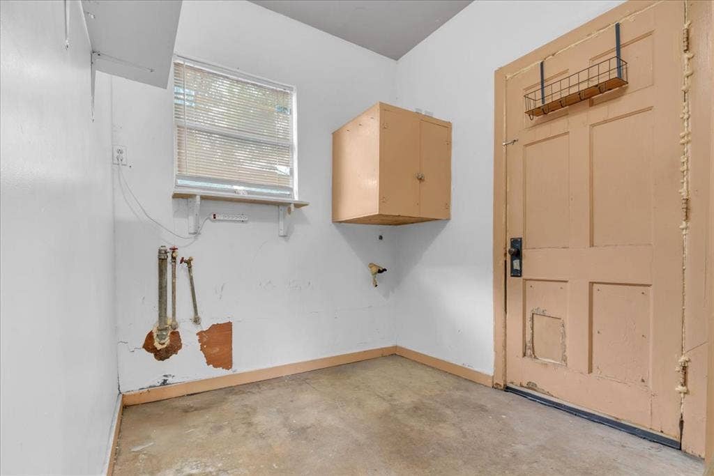 1113 Hudgins Avenue, Fort Worth, TX 76111 Utility room featuring a window with blinds, wall-mounted cabinetry, and exposed plumbing hookups