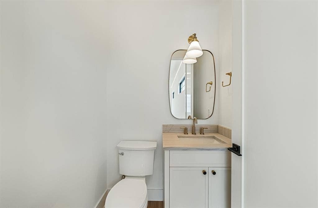 3723 Manana Drive, Dallas, TX 75220 Powder room featuring a white single vanity with light-toned countertop, an integrated sink, and gold-finish hardware