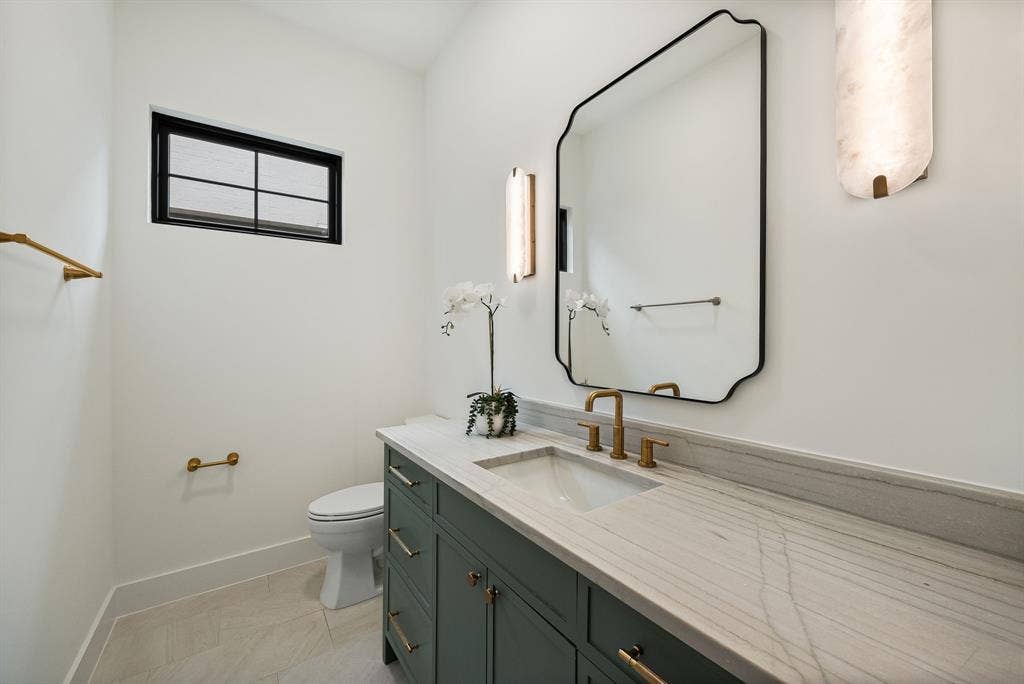 3723 Manana Drive, Dallas, TX 75220 Bathroom featuring a green vanity with brass hardware, a white undermount sink, and a light-toned countertop
