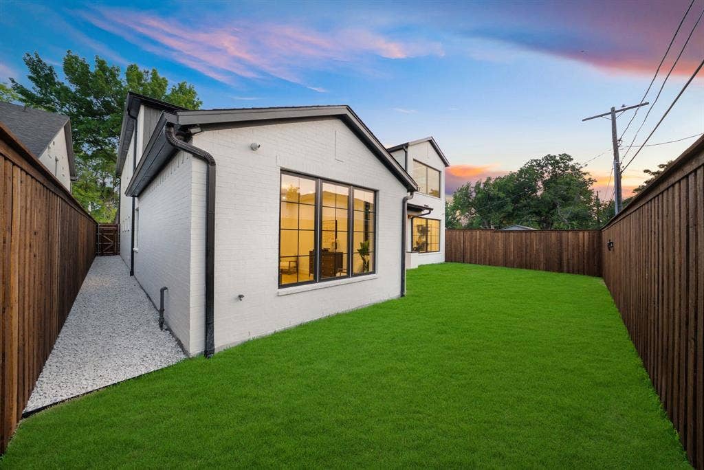 3723 Manana Drive, Dallas, TX 75220 Modern residence featuring a spacious backyard with lush manicured lawn, mature landscaping, and wood-finish privacy fencing