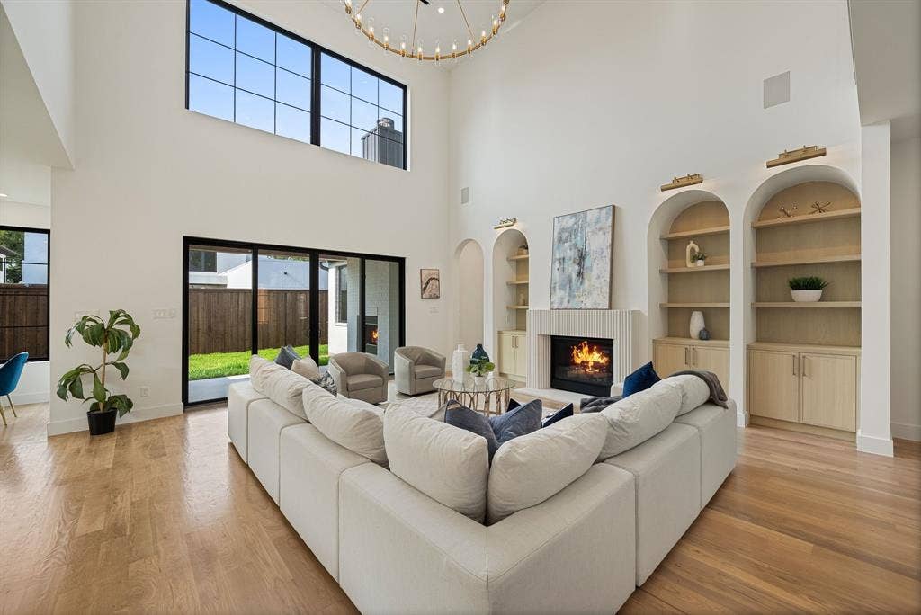 3723 Manana Drive, Dallas, TX 75220 Spacious living area featuring a vaulted ceiling, a fireplace with a fluted surround, and custom arched built-in shelving