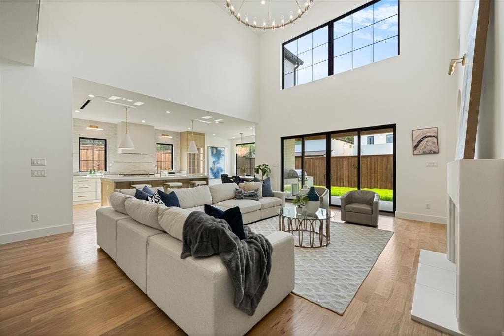 3723 Manana Drive, Dallas, TX 75220 Open-concept living space featuring high ceilings, wood-finish flooring, and a fireplace with a white mantel