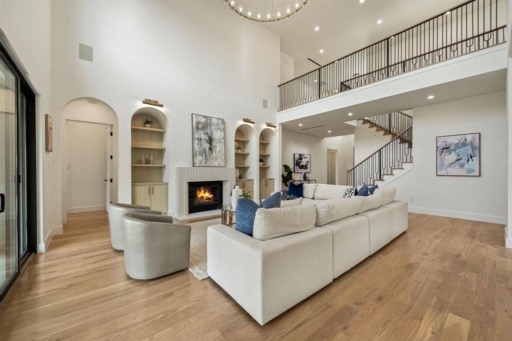 3723 Manana Drive, Dallas, TX 75220 Two-story living area featuring wood-finish flooring, a contemporary fireplace with a vertical tile surround, and arched built-in shelving