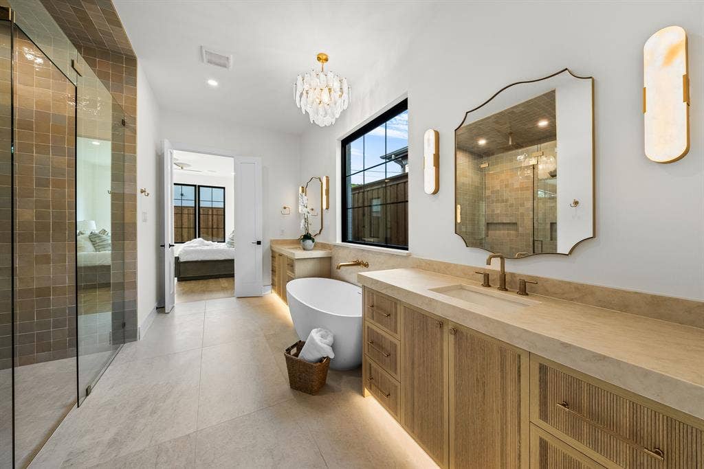 3723 Manana Drive, Dallas, TX 75220 Contemporary bathroom featuring a freestanding tub, dual vanities with integrated sinks, a walk-in shower with glass enclosure, and large format floor tiling