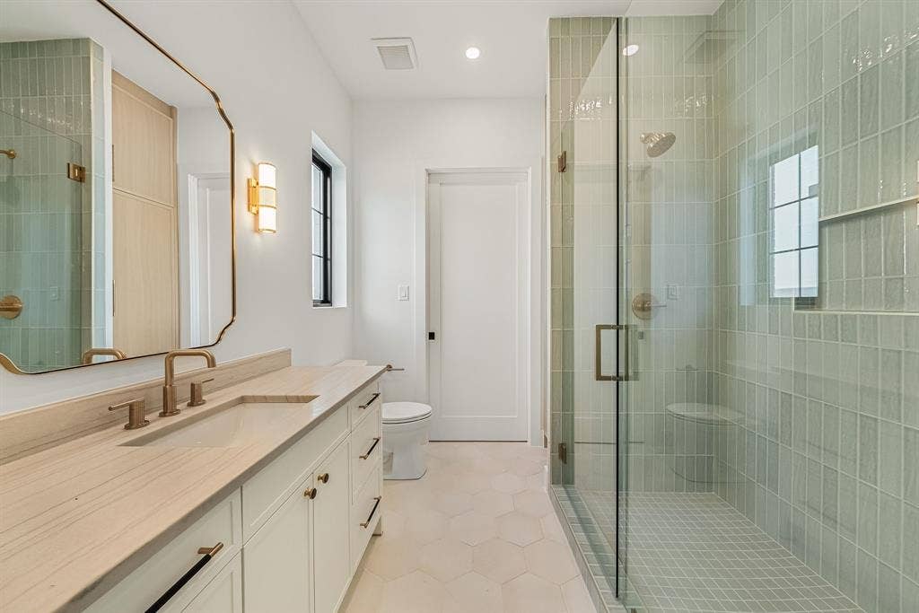 3723 Manana Drive, Dallas, TX 75220 Bathroom featuring a glass-enclosed shower with vertical tile, a built-in shower bench, and a rectangular niche