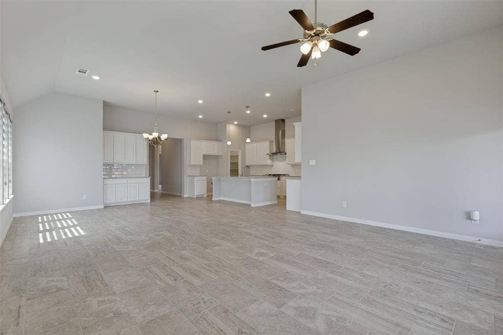 12464 Lost Valley Drive, Frisco, TX 75035 Spacious open-concept interior featuring light gray tile flooring, vaulted ceilings, and recessed lighting