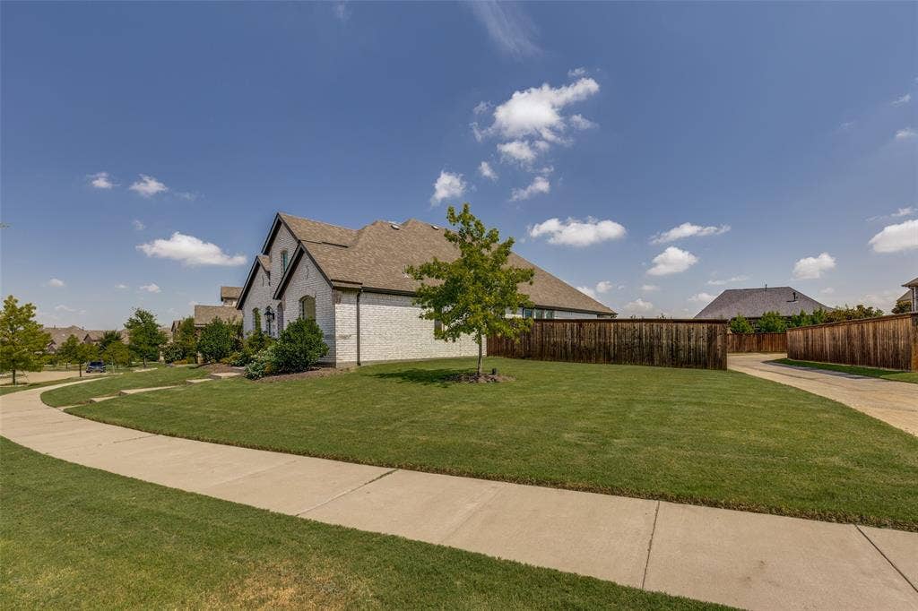 12464 Lost Valley Drive, Frisco, TX 75035 White brick exterior with dark trim and a brown shingle roof