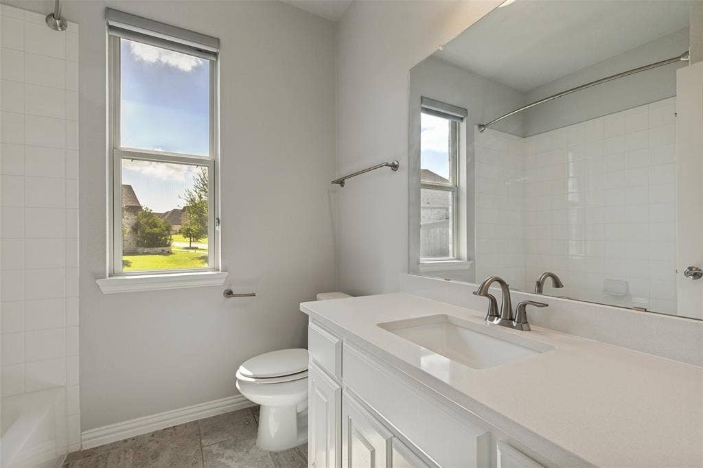 12464 Lost Valley Drive, Frisco, TX 75035 Bathroom featuring a white vanity with an integrated sink and brushed nickel faucet, a large rectangular mirror, and a window with a roller shade