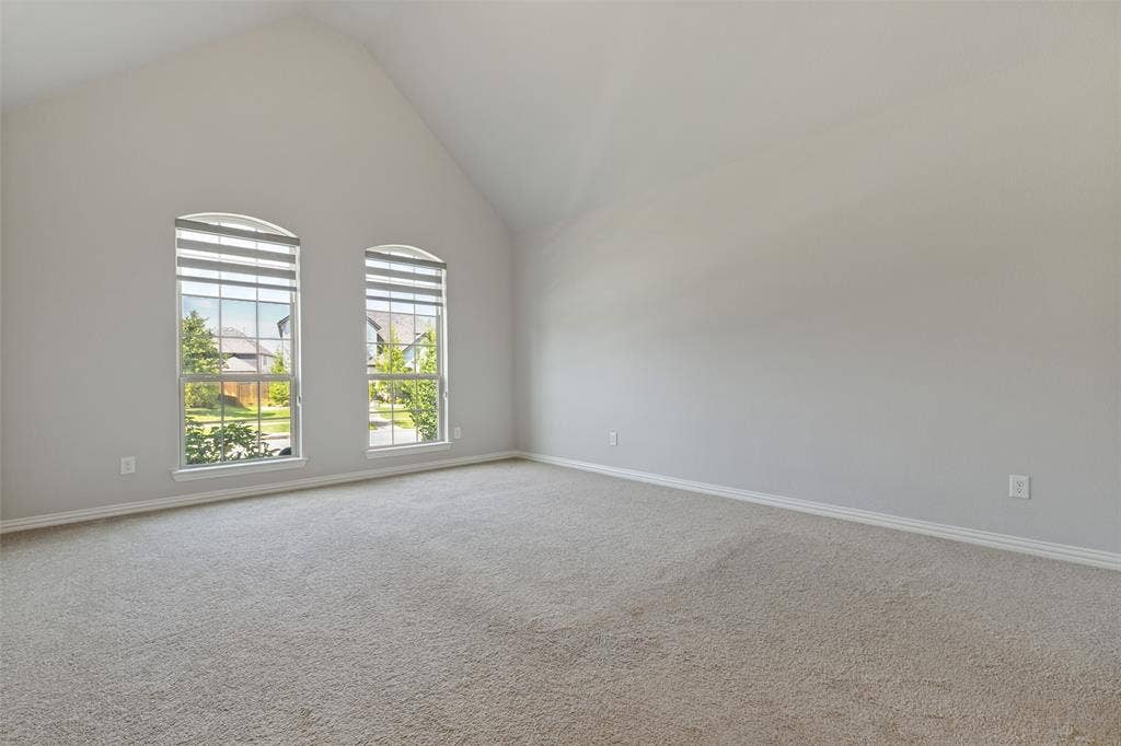 12464 Lost Valley Drive, Frisco, TX 75035 Vaulted ceiling room featuring twin arched windows with louvered blinds, carpeting, and neutral wall tones