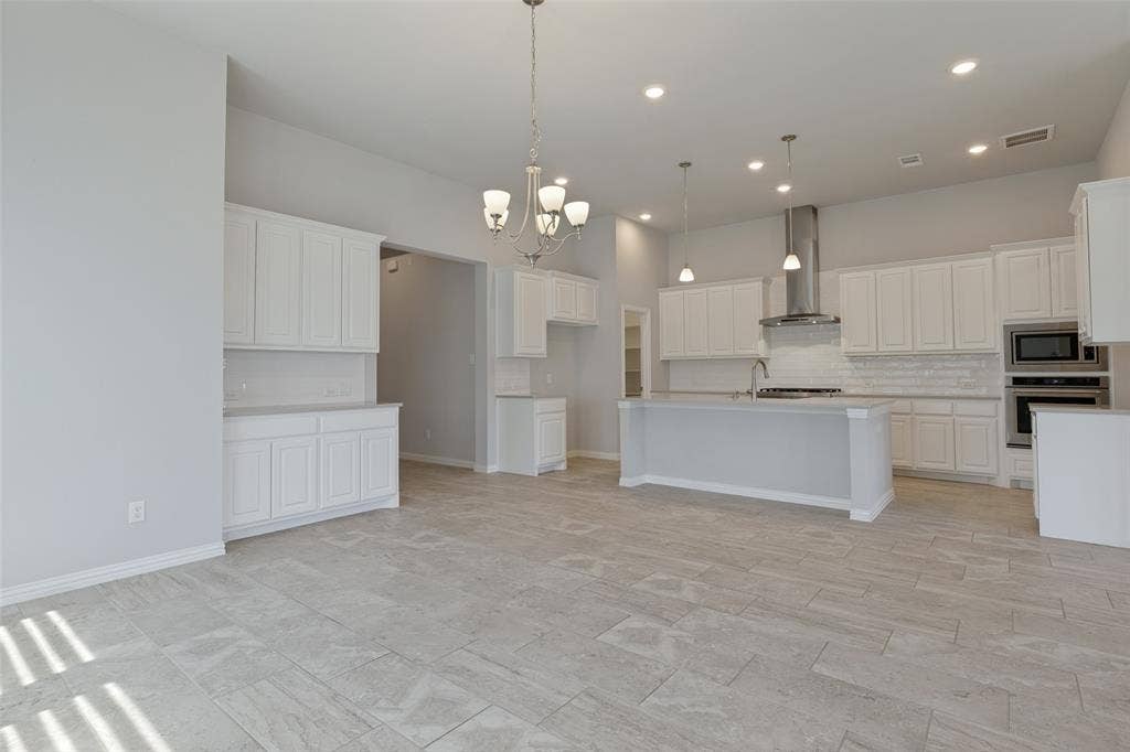 12464 Lost Valley Drive, Frisco, TX 75035 Open-concept kitchen featuring an oversized island, white shaker cabinetry, stainless steel appliances, a subway tile backsplash, and recessed lighting