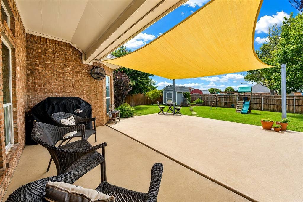 5304 Fox Run Drive, Watauga, TX 76137 Enjoy outdoor living at its best on the expansive covered patio featuring a large shade sail, extended concrete patio and two fans mounted in the corners.