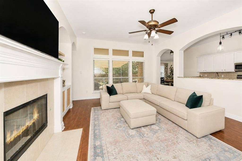 5304 Fox Run Drive, Watauga, TX 76137 The inviting family room features rich wood flooring, a cozy gas fireplace with a classic mantel, soaring ceilings, and an open-concept layout that seamlessly connects to the kitchen, creating the perfect space for relaxing and entertaining.