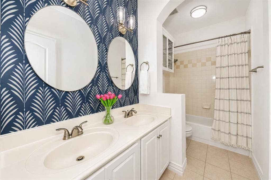 5304 Fox Run Drive, Watauga, TX 76137 The beautifully appointed hall bath serving the secondary bedrooms features a dual-sink vanity, stylish designer wallpaper, modern lighting, and a tub/shower combination, offering both elegance and everyday functionality for family and guests.