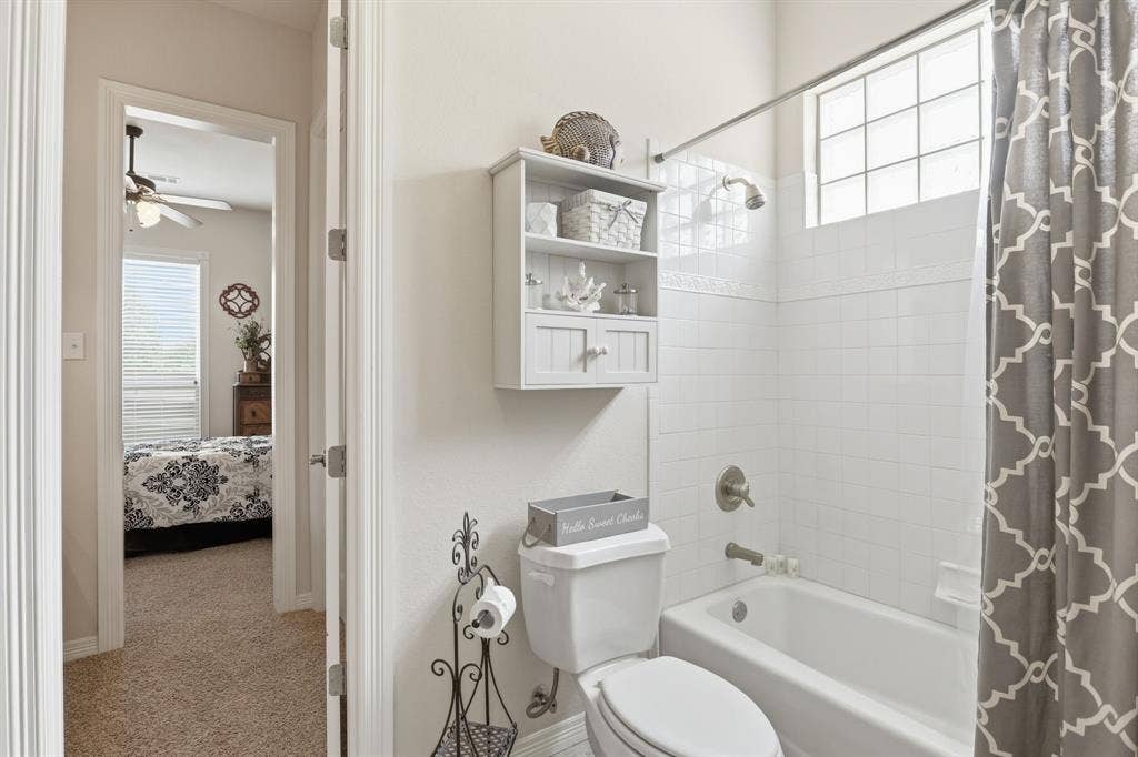 5030 Monroe Court, Midlothian, TX 76065 Bathroom featuring a white bathtub, ceramic tile surround, and a glass block window for natural light