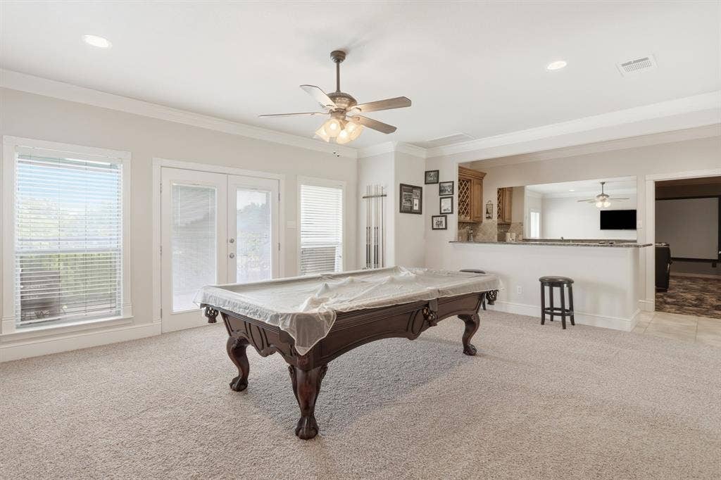 5030 Monroe Court, Midlothian, TX 76065 Spacious entertainment room featuring recessed lighting, crown molding, a built-in wet bar with wood cabinetry, and double glass-panel doors