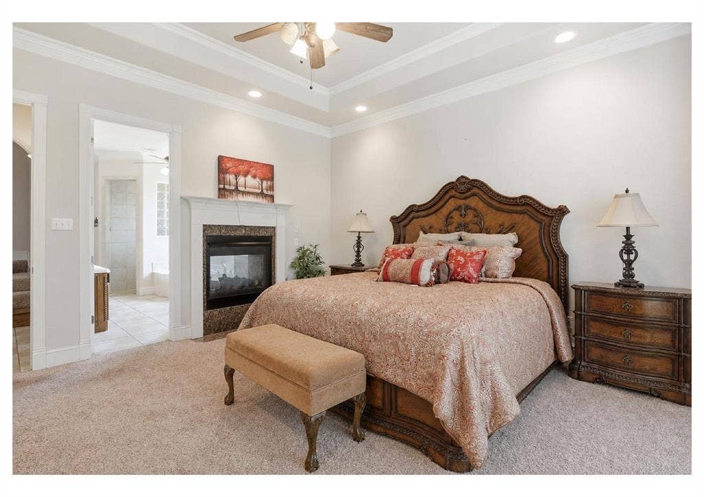 5030 Monroe Court, Midlothian, TX 76065 Carpeted bedroom featuring a tray ceiling, recessed lighting, and a built-in fireplace with a stone surround