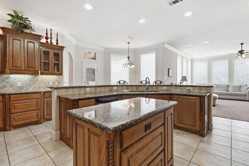5030 Monroe Court, Midlothian, TX 76065 Kitchen featuring a central island with a stone-finish countertop, wood cabinetry, and a tile backsplash