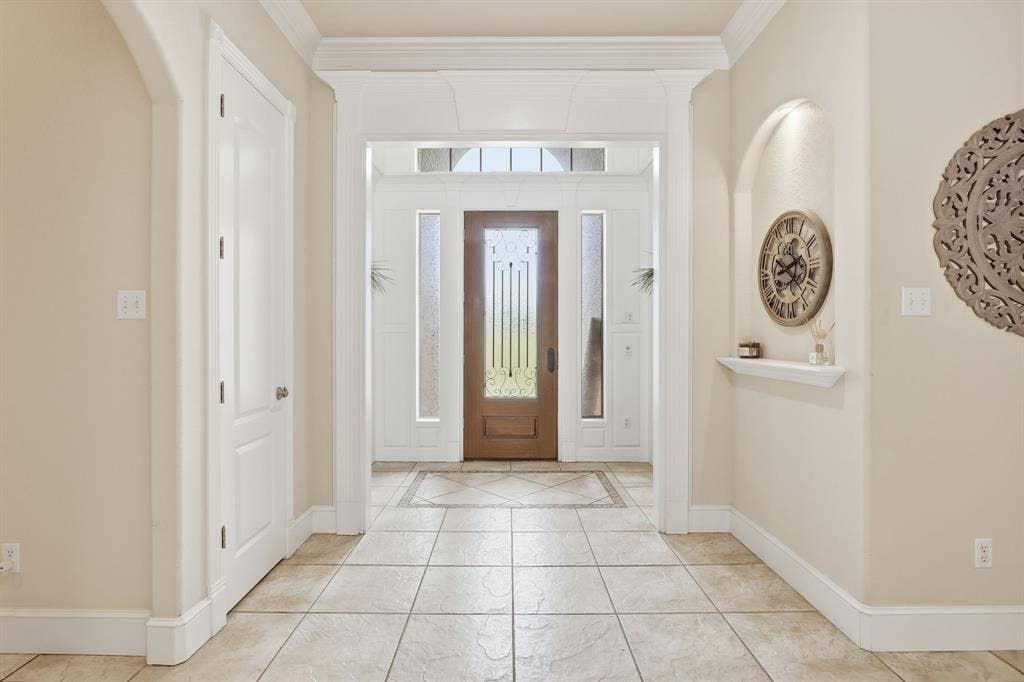 5030 Monroe Court, Midlothian, TX 76065 Entry foyer featuring tile flooring with a decorative inlay, an arched wall niche with integrated lighting, a solid wood front door with decorative glass, and sidelight windows with frosted glass
