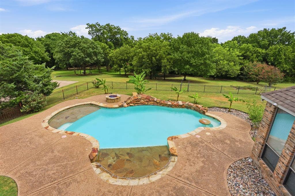 5030 Monroe Court, Midlothian, TX 76065 Kidney-shaped swimming pool featuring a rock waterfall, surrounded by an exposed aggregate concrete patio