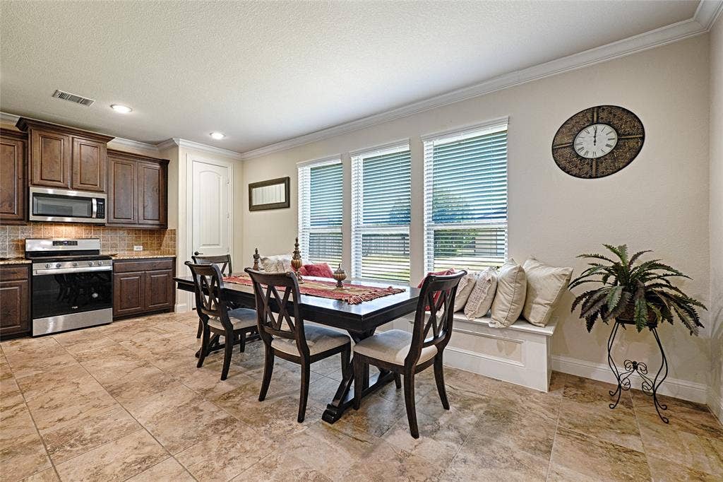 Kitchen and dining area featuring wood cabinetry, stainless steel appliances, and a tiled backsplash