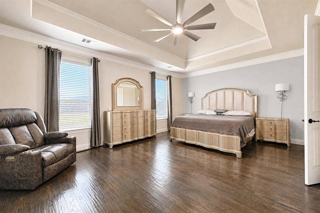 Spacious room featuring wood-finish flooring, a tray ceiling, and crown molding