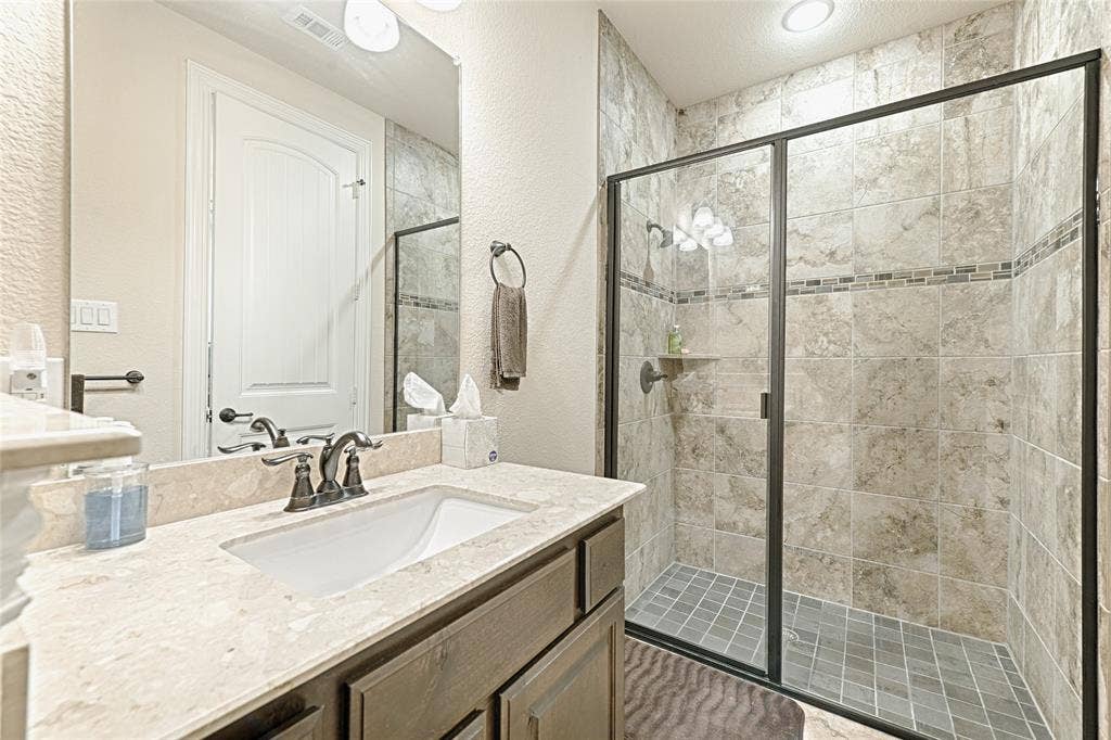 Bathroom featuring a glass-enclosed shower with tile surround and mosaic accent band