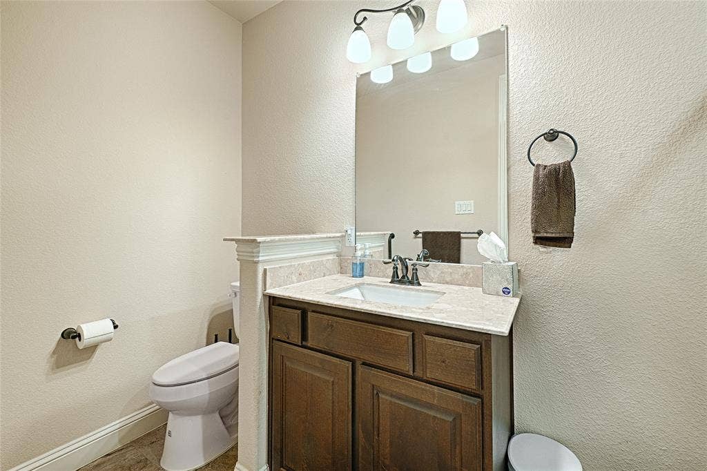 Bathroom vanity featuring a light-colored countertop, integrated sink, and wood-panel cabinetry