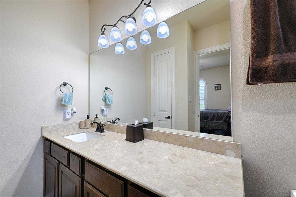 Bathroom vanity featuring a single basin, dark wood-finish cabinetry, and a stone countertop