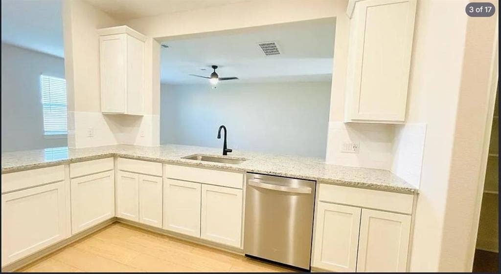 1323 windermere Way, Princeton, TX 75407 Kitchen featuring light wood-finish flooring, white cabinetry, speckled countertops, a stainless steel dishwasher, and a black gooseneck faucet