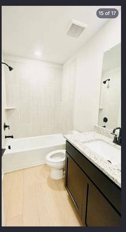 1323 windermere Way, Princeton, TX 75407 Bathroom featuring a white bathtub, light-toned vertical tile surround with an integrated niche, black fixtures, dark wood-finish vanity with a white countertop and integrated sink, and light wood-finish flooring