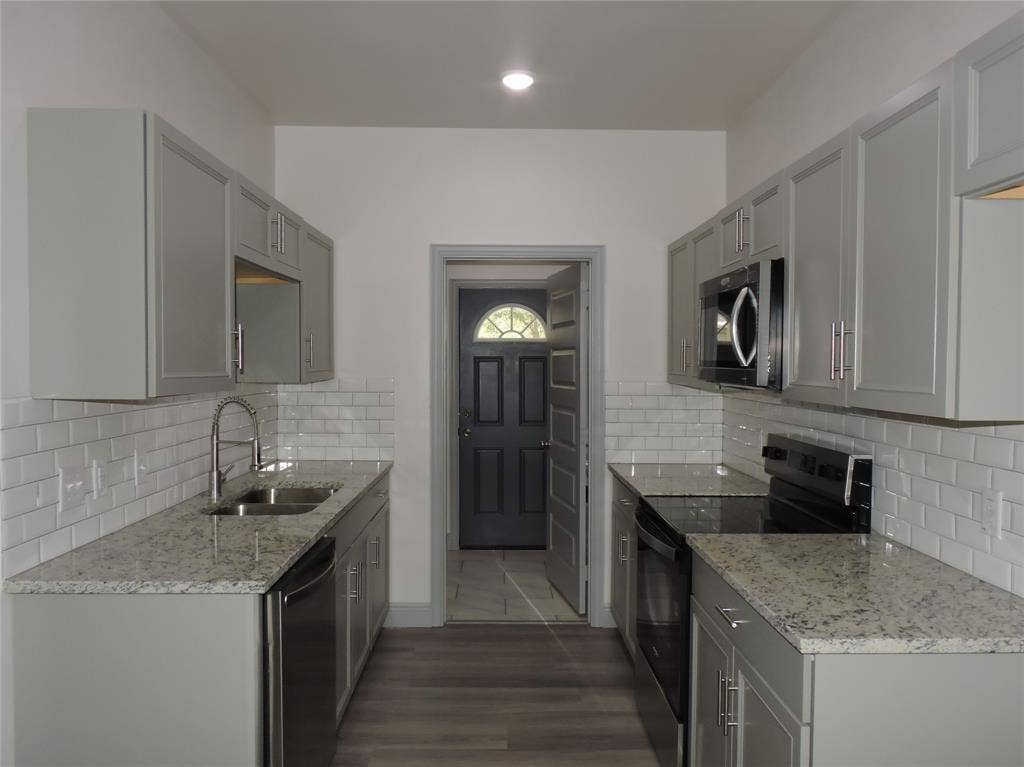 6110 Tejas Drive, Mabank, TX 75156 Galley kitchen featuring light gray cabinetry, speckled countertops, stainless steel appliances, white subway tile backsplash, and wood-finish flooring