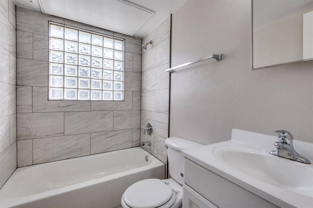 4915 Reiger Avenue, #D, Dallas, TX 75214 Bathroom featuring a tub/shower combination, glass block window, chrome fixtures, white vanity with integrated sink, and large format tile surround