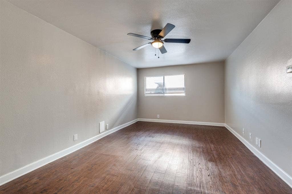 4915 Reiger Avenue, #D, Dallas, TX 75214 Spacious room featuring wood-finish flooring, neutral-toned walls, a ceiling fan with integrated lighting, and a window with horizontal blinds