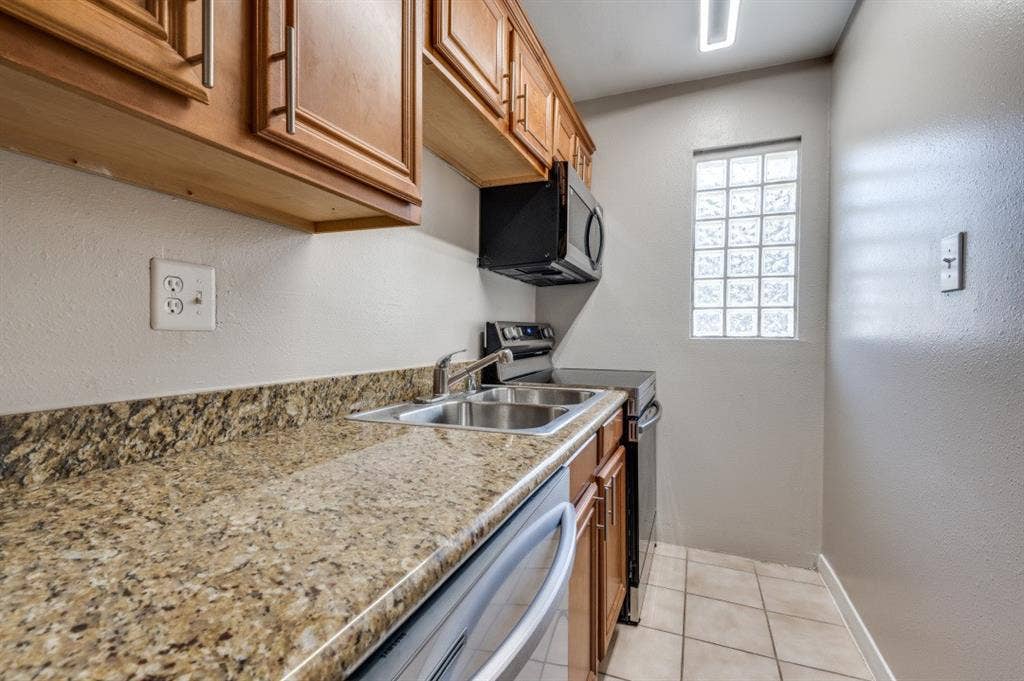 4915 Reiger Avenue, #D, Dallas, TX 75214 Kitchen featuring wood cabinetry, granite-finish countertops, and a double basin stainless steel sink