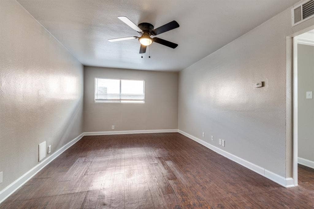 4915 Reiger Avenue, #D, Dallas, TX 75214 Spacious room featuring wood-finish flooring, light gray walls, a ceiling fan with integrated lighting, and a window with blinds