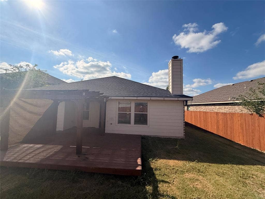 2004 Samantha Lane, Heartland, TX 75126 Expansive backyard featuring a wood deck with a pergola, a sloped grassy area, a wooden privacy fence, and a visible chimney