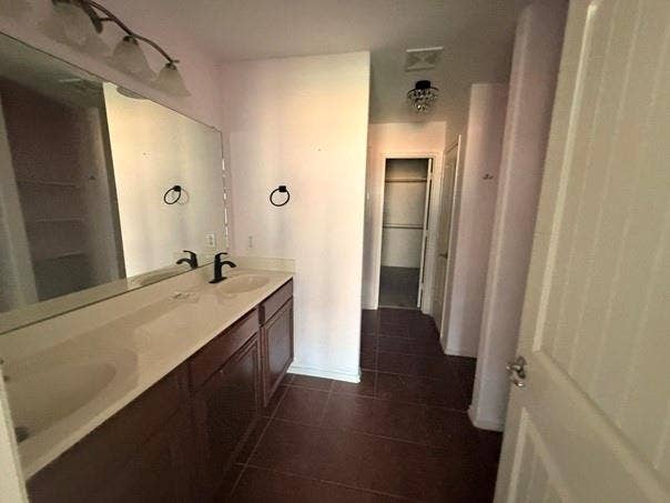2004 Samantha Lane, Heartland, TX 75126 Bathroom vanity featuring two integrated sinks, dark wood cabinetry, a large wall-mounted mirror, and a three-light fixture