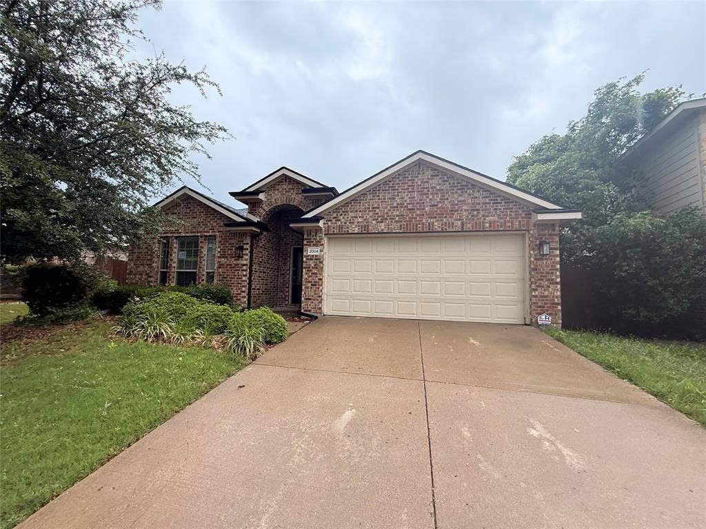 2004 Samantha Lane, Heartland, TX 75126 Brick exterior featuring a two-car garage, concrete driveway, and established front landscaping
