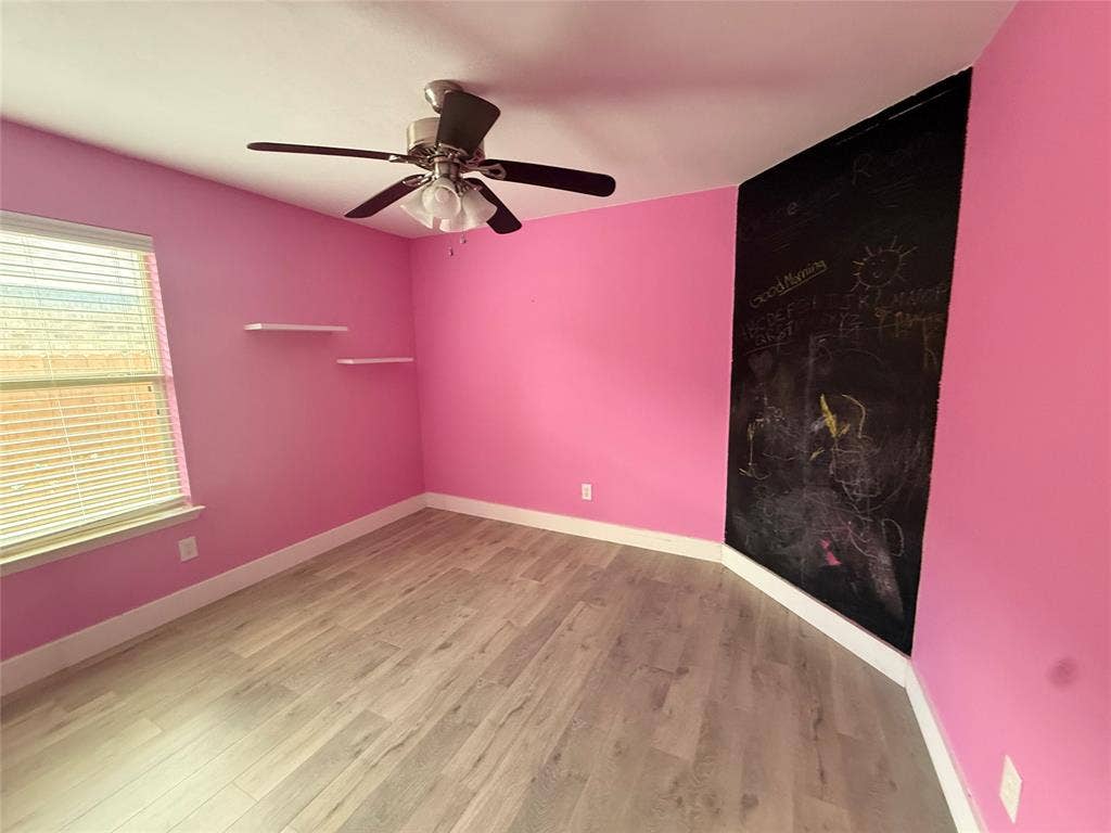 2004 Samantha Lane, Heartland, TX 75126 Room featuring wood-finish flooring, a ceiling fan with integrated lighting, a window with horizontal blinds, built-in floating wall shelves, and a chalkboard wall panel