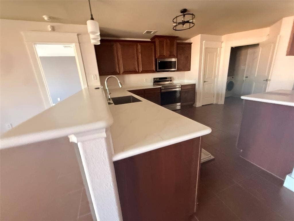 2004 Samantha Lane, Heartland, TX 75126 Kitchen featuring a stainless steel sink with gooseneck faucet, light-toned countertops, and rich wood-finish cabinetry